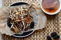 Chinese traditional medicine script. Herbal tea with jujubes, goji berries, gingseng roots and others on parchment paper on neutr