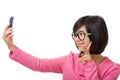 Asian woman using a cell phone to take a selfie isolated on white background Royalty Free Stock Photo