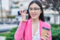 Chinese woman business worker listening voice message by smartphone drinking coffee at park Royalty Free Stock Photo