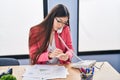 Chinese woman business worker talking on telephone writing on reminder paper at office