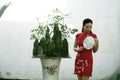 Chinese woman in cheongsam in Mudu ancient town by a bonsai trees and mountains