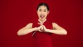 Chinese woman in red dress posing respecting, smiling and greeting on red color backgroun to celebrate Chinese New Year