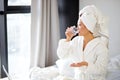 chinese woman taking a pill, sitting on her bed at home, wearing bathrobe and towel Royalty Free Stock Photo