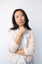 Thoughtful Asian business woman posing against white background.
