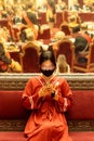 Chinese woman wearing facial mask sitting in museum, using smartphone