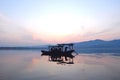 Chinese wooden boat drifting on a lake in sunset