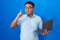 Chinese young man using computer laptop pointing finger up with successful idea Royalty Free Stock Photo