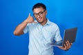 Chinese young man using computer laptop smiling doing phone gesture with hand and fingers like talking on the telephone Royalty Free Stock Photo