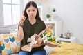 Chinese young woman holding bouquet of white flowers pointing up looking sad and upset, indicating direction with fingers, unhappy Royalty Free Stock Photo