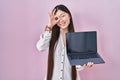 Chinese young woman holding laptop showing screen smiling happy doing ok sign with hand on eye looking through fingers Royalty Free Stock Photo