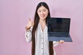 Chinese young woman holding laptop showing screen smiling happy and positive, thumb up doing excellent and approval sign Royalty Free Stock Photo