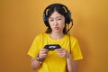 Chinese young woman playing video game holding controller puffing cheeks with funny face Royalty Free Stock Photo