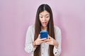 Chinese young woman using smartphone typing message celebrating crazy and amazed for success with open eyes screaming excited Royalty Free Stock Photo