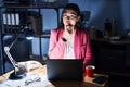 Chinese young woman working at the office at night looking confident at the camera with smile with crossed arms and hand raised on Royalty Free Stock Photo