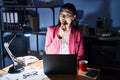 Chinese young woman working at the office at night looking confident at the camera smiling with crossed arms and hand raised on Royalty Free Stock Photo