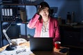 Chinese young woman working at the office at night smiling and laughing with hand on face covering eyes for surprise Royalty Free Stock Photo