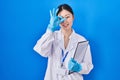 Chinese young woman working at scientist laboratory doing ok gesture with hand smiling, eye looking through fingers with happy Royalty Free Stock Photo