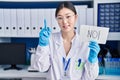 Chinese young woman working at scientist laboratory holding no banner surprised with an idea or question pointing finger with