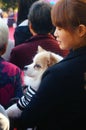 Chinese young women hold pet dogs in crowds watching entertainment