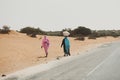 Chinguetti, Adrar Province, Mauritania, January 20, 2020: woman in traditional clothes carries a bag along the road. Still many