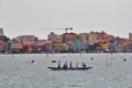 Chioggia, Italy, the sea, a boat with people in colorful t-shirts, colorful houses in the background, people on a long boat