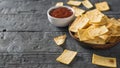 Chips from a Mexican tortilla with tomato sauce on the black wooden table. Royalty Free Stock Photo