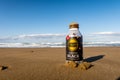 Chirihama Beach Driveway, Noto, Japan, 10/11/19. Bottle of hot Tully`s Coffee Barista`s Black buried in the sand on the beach.