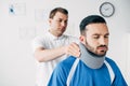 Chiropractor examining good-looking football player in neck brace