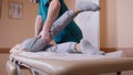 Chiropractor massaging a young woman lying on a massage table, stretching and flexing her feet and knee, close-up of Royalty Free Stock Photo