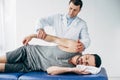 Chiropractor stretching arm of handsome patient lying on massage table Royalty Free Stock Photo