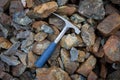 Chisel edge rock pick, geologist exploration tool over natural rocks background in abandoned chromite mine