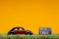 Chisinau, Moldova - August 15th 2019: A crimson car figurine aligned to the left on grass next to a sign which says test drive