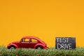 Chisinau, Moldova - August 15th 2019: A red car figurine aligned to the left on grass next to a sign which says test drive