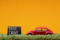 Chisinau, Moldova - August 15th 2019: A red car figurine aligned to the right on grass next to a sign which says test drive