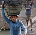 male worker is busy to loading a coal truck on his head . He is working without any safety equipment.