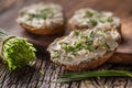 Chive cream cheese spread on a bread slices next to bunch of freshly cut chives on a rustic wood and chopping board Royalty Free Stock Photo
