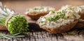 Chive cream cheese spread on a bread slices next to bunch of freshly cut chives on a rustic wood and chopping board Royalty Free Stock Photo