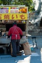 Chiyoda City, Tokyo, Japan - January 02, 2020: A Japanese man selling baked sweet potatoes outside the traditional Yasukuni Shrine