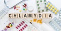 Chlamydia - word from wooden blocks with letters, parasitic bacterium chlamydia concept with pills, vitamins, stethoscope and