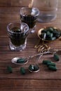 Chlorella shots and spirulina pills on a rustic table Royalty Free Stock Photo