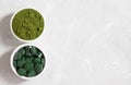 Chlorella and spirulina in bowls on a white concrete background. Tablets and powder form. Detox superfood. Healthy supplement. Royalty Free Stock Photo