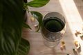 Chlorophyll extract is poured into clean water in a glass on a wooden background with a green leaf. Liquid chlorophyll in a glass Royalty Free Stock Photo