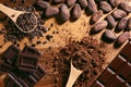 Chocolate bar, cocoa powder, cacao beans and nibs, heap in wooden spoons, chocolate background Royalty Free Stock Photo