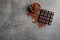 Chocolate bar and cocoa powder on grey, flat lay. Space for text Royalty Free Stock Photo