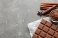 Chocolate bar and cocoa powder on grey, flat lay. Space for text Royalty Free Stock Photo