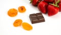 Chocolate bar sits on a white table next to a bowl of fruit Royalty Free Stock Photo
