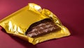 A chocolate bar is sitting in a gold wrapper Royalty Free Stock Photo