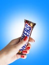 Chocolate bar Snickers to a female hand.