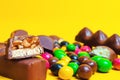 Chocolate bars, colorful candies, sweets on a yellow background Royalty Free Stock Photo