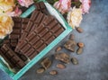 Chocolate bars in a vintage box. Chocolate beans, flowers,pieces of chocolate scattered on a textural background